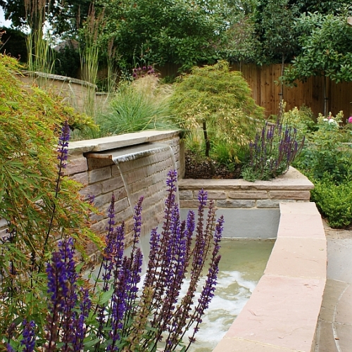 A modern water feature cascades down into the wide pool below
